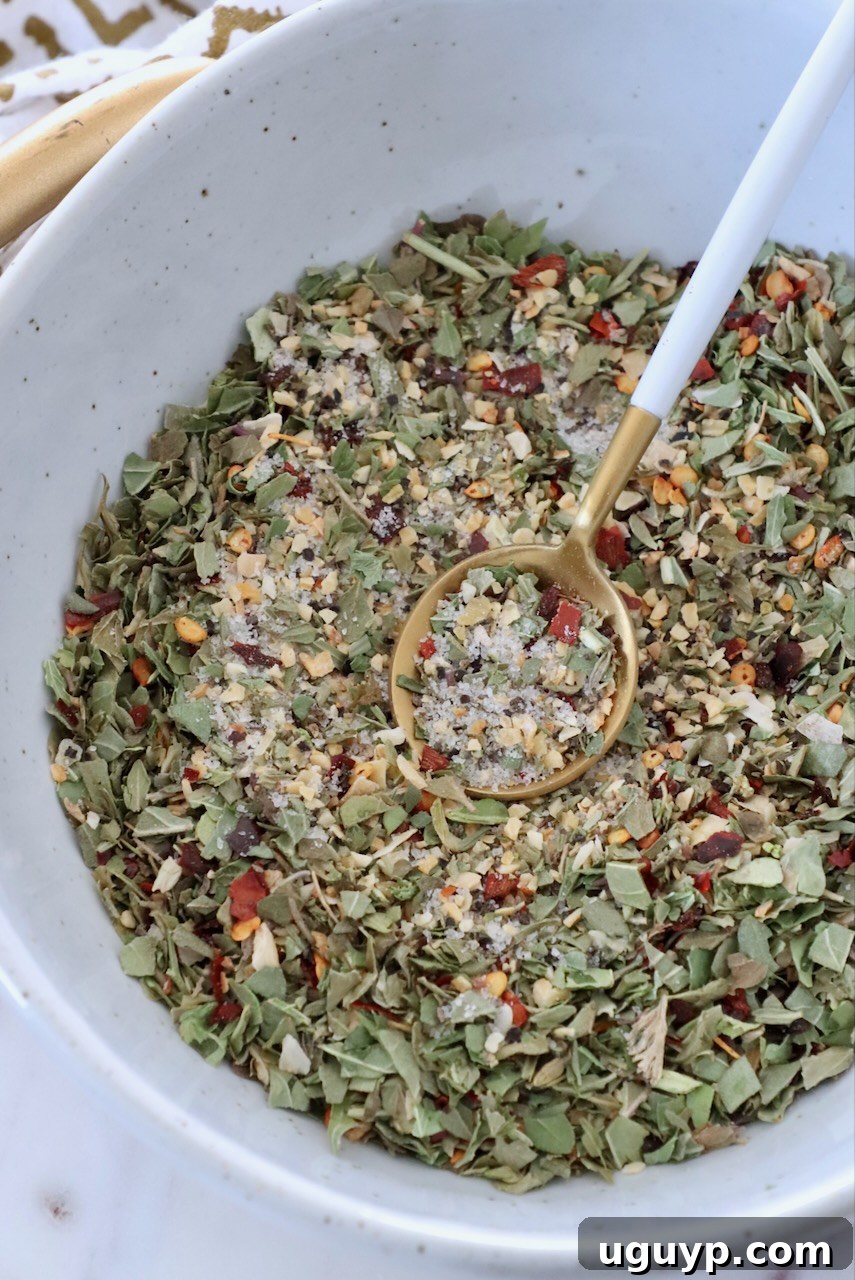 A full bowl of Italian dressing seasoning mix with a spoon, ready for use.