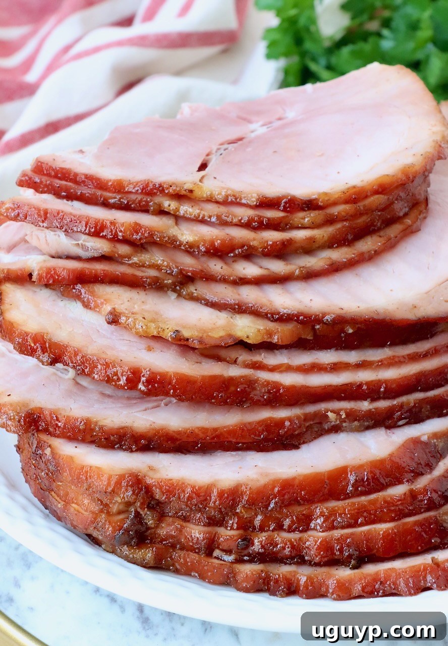 slices of ham stacked up on a plate, showcasing its juicy interior and caramelized crust