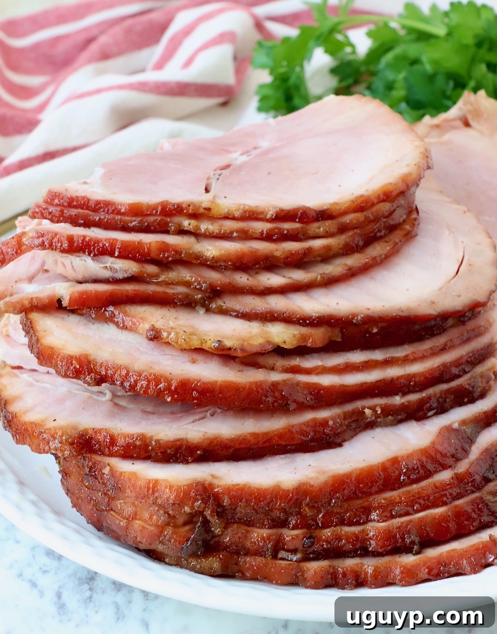 close up of sliced ham stacked up on a plate, showing the texture and glaze