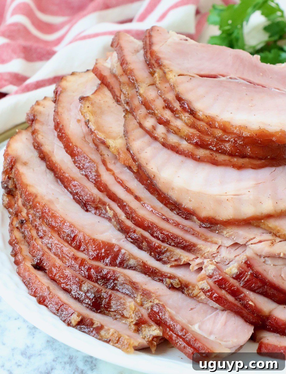 close up of perfectly sliced honey baked ham on a white plate