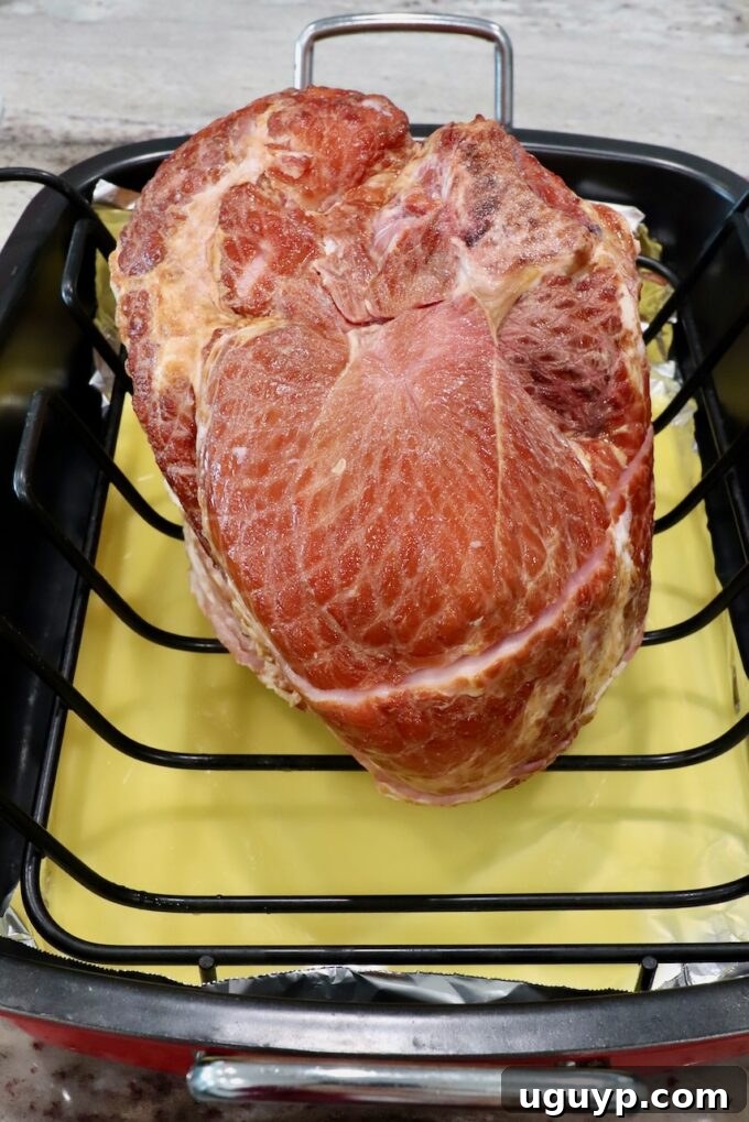 spiral ham in roasting pan with pineapple juice poured at the bottom