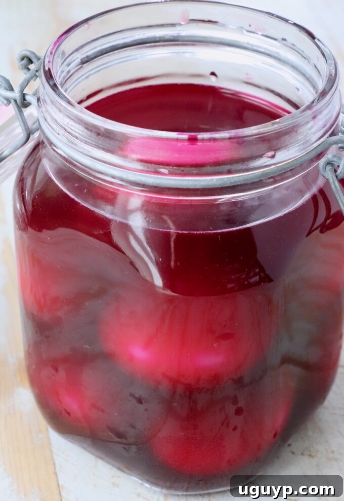 Hard boiled eggs soaking in rich red pickled beet juice inside a glass jar