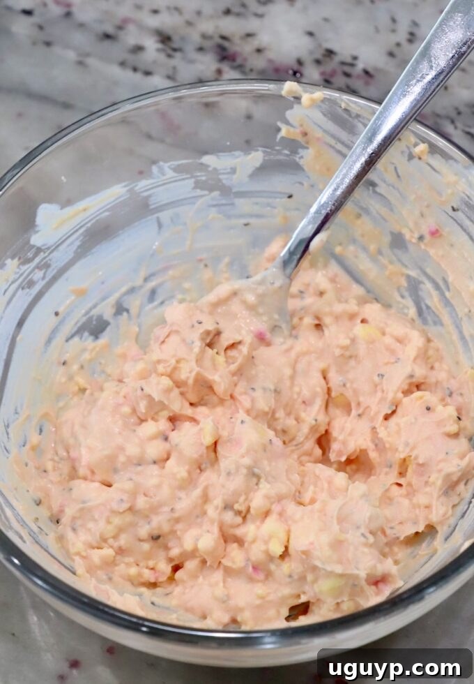 Creamy beet pickled deviled egg filling in a glass bowl with a spoon, showing its smooth texture