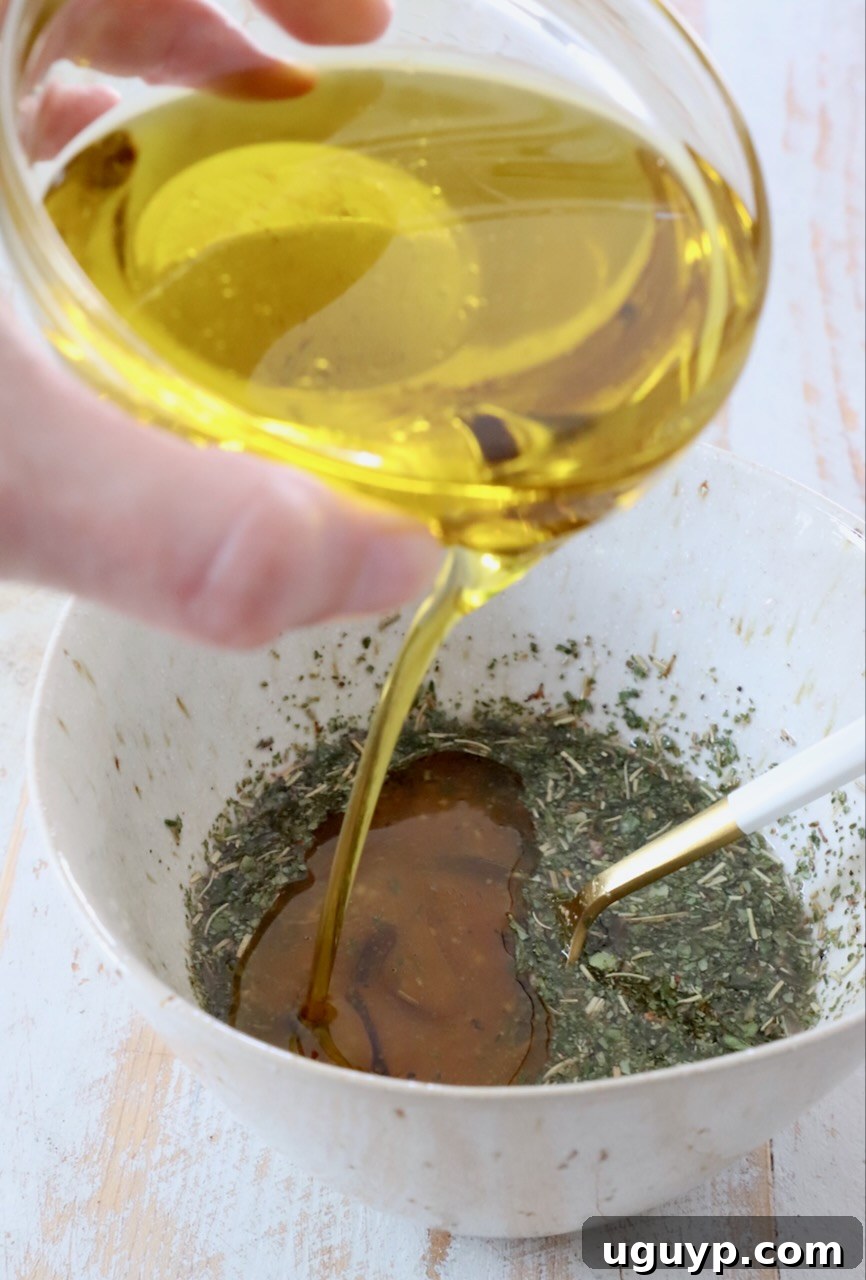oil poured into bowl with vinegar and herbs