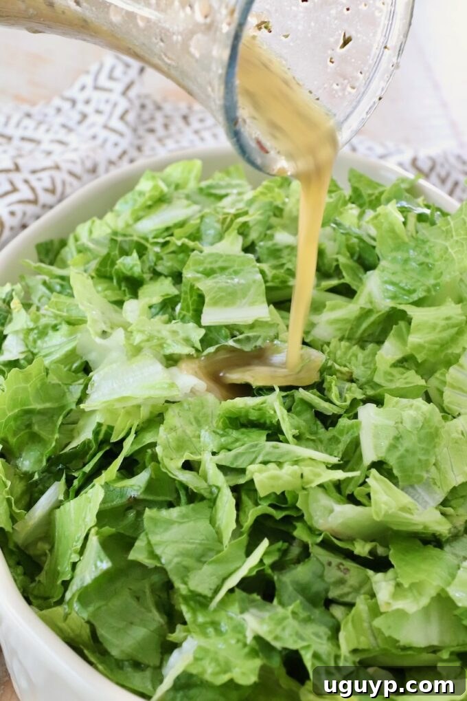 salad dressing poured onto a bowl of chopped greens