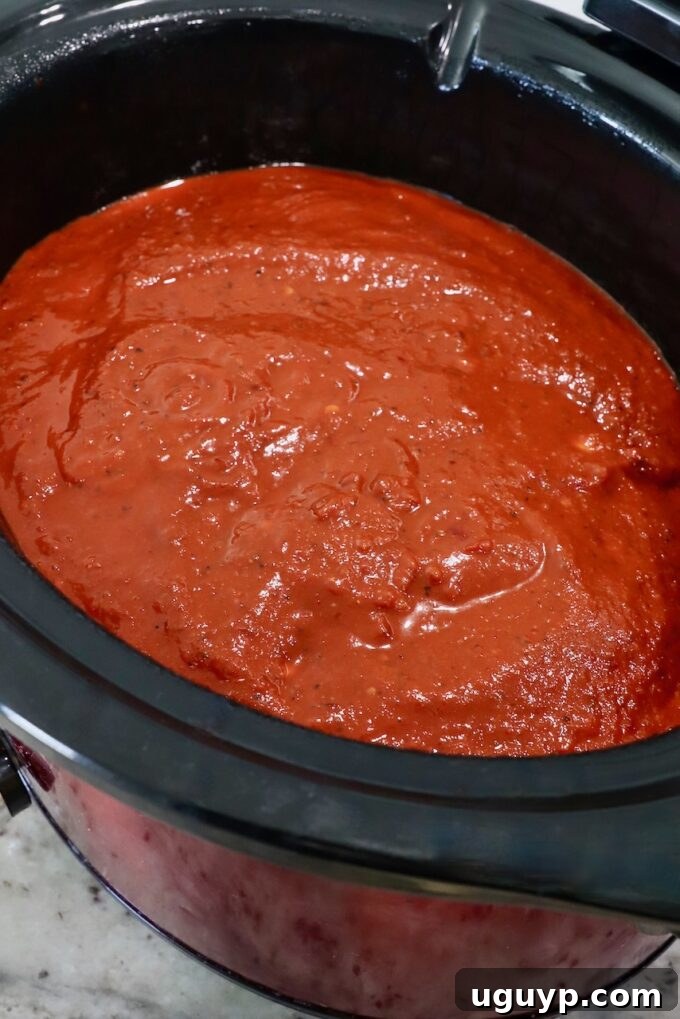chicken thighs covered in tomato chili sauce in slow cooker