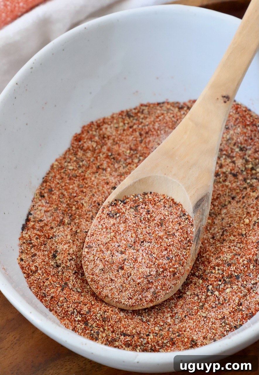 A bowl of rich, homemade hamburger seasoning with a wooden spoon, ready to enhance any burger recipe.