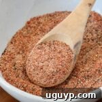 A bowl of homemade hamburger seasoning with a spoon, highlighting its texture and richness.
