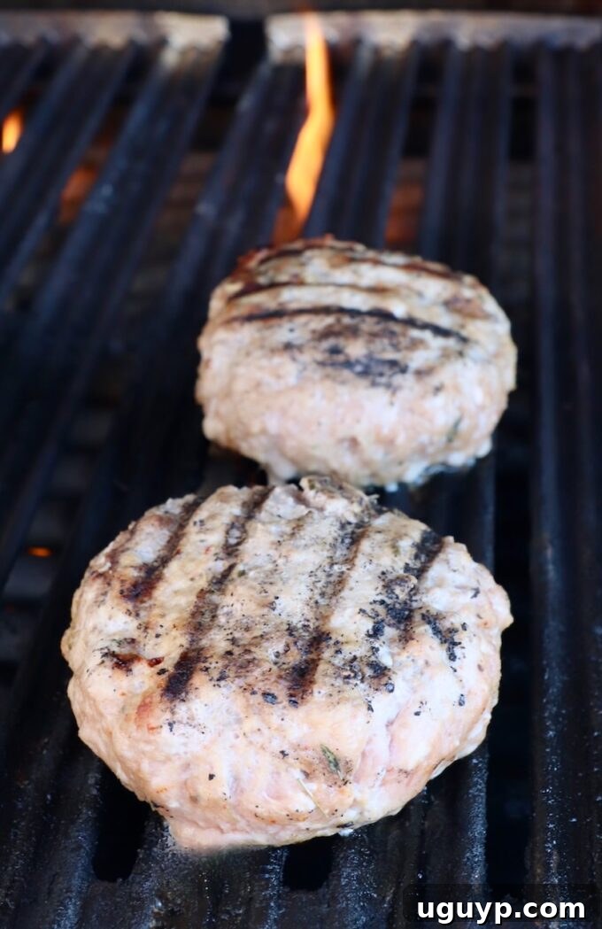 Perfectly grilled turkey burger patties with grill marks, still on the grill