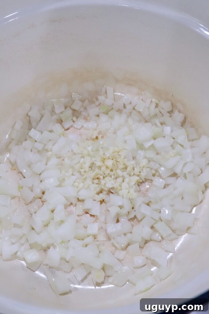 Diced yellow onions and minced garlic cloves sizzling in olive oil in a large stockpot.