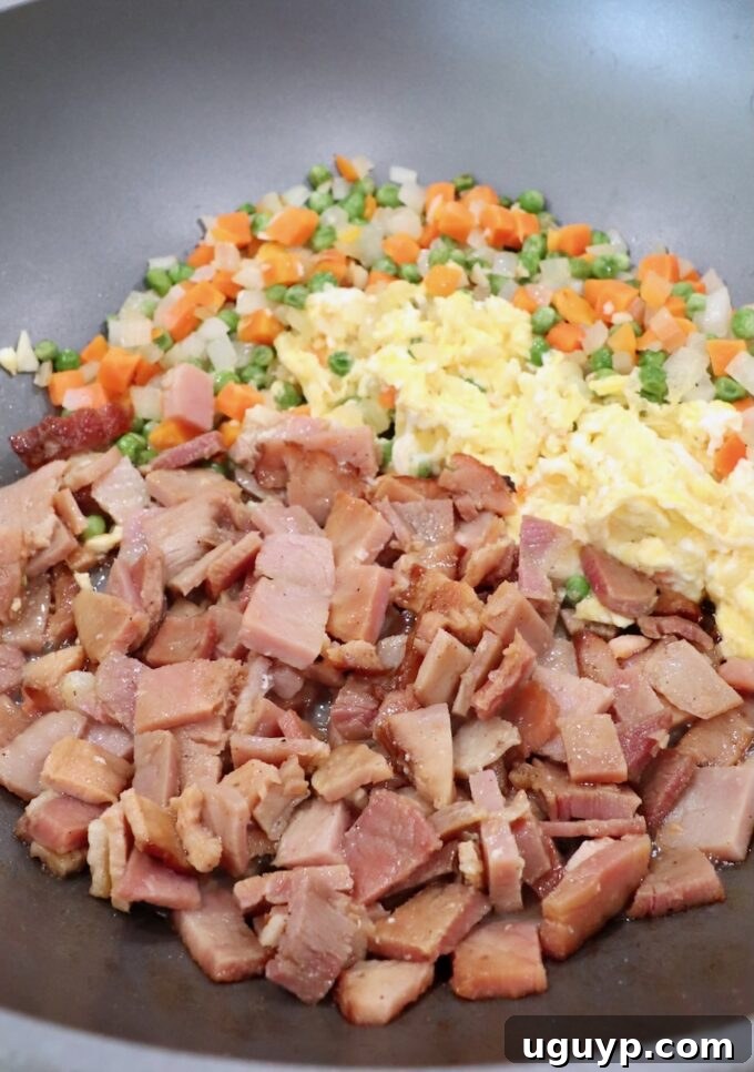 diced ham frying in a skillet with scrambled eggs and mixed vegetables