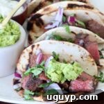 steak tacos topped with guacamole on plate