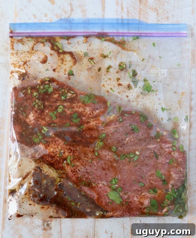 Flat iron steak marinating in a sealed zipper bag with lime juice, oil, agave, and spices.
