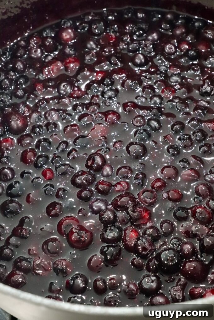 Cooked blueberry pie filling in a large saucepan, showing a thick, glossy consistency.