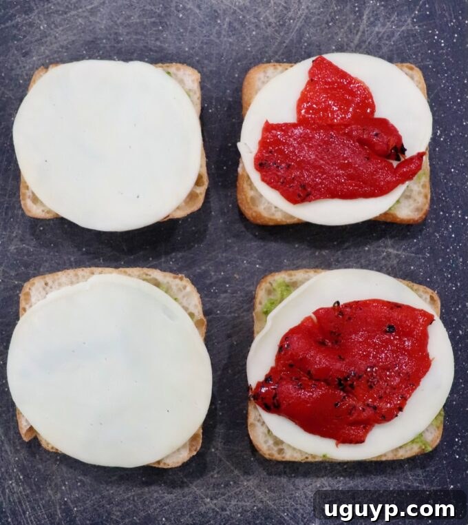 Roasted red peppers placed on top of sliced provolone cheese on ciabatta rolls
