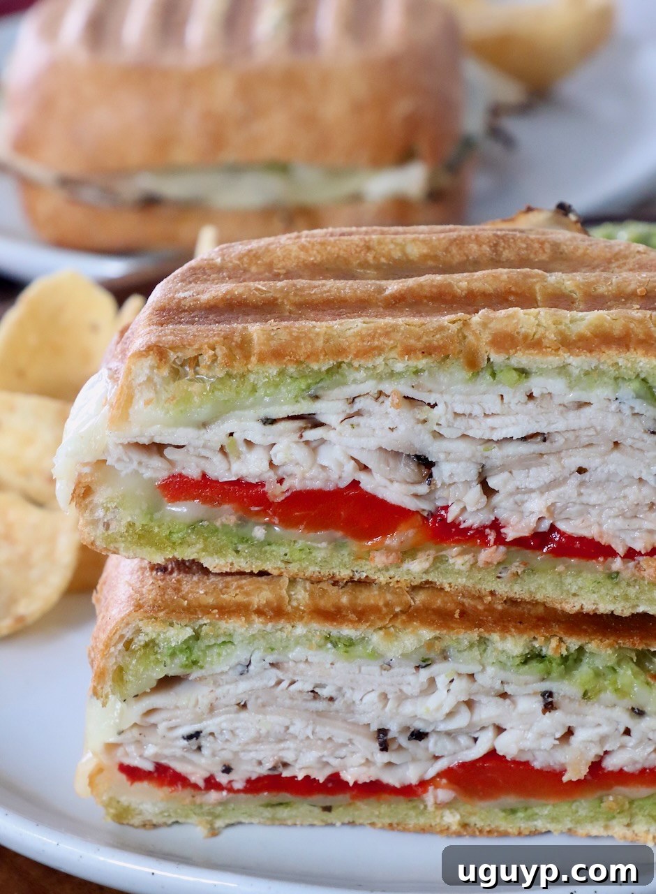 Turkey panini sliced in half and stacked on a plate, showcasing its melted cheese and layers