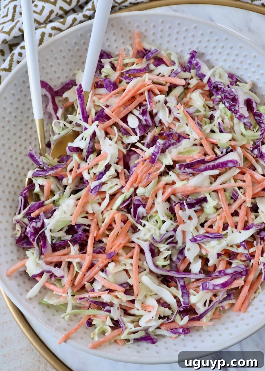 prepared coleslaw in large bowl with spoons
