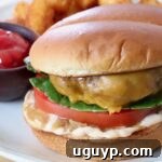Cheeseburger on a plate with a side bowl of ketchup, ready to eat.