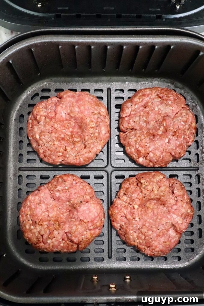 Raw burger patties placed in an air fryer basket, spaced evenly for optimal cooking.