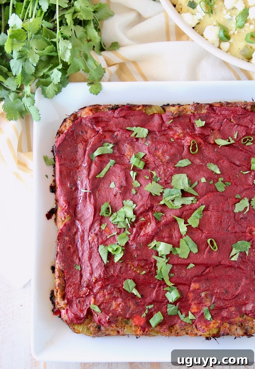 Cooked Mexican meatloaf on white plate topped with tomato paste and cilantro