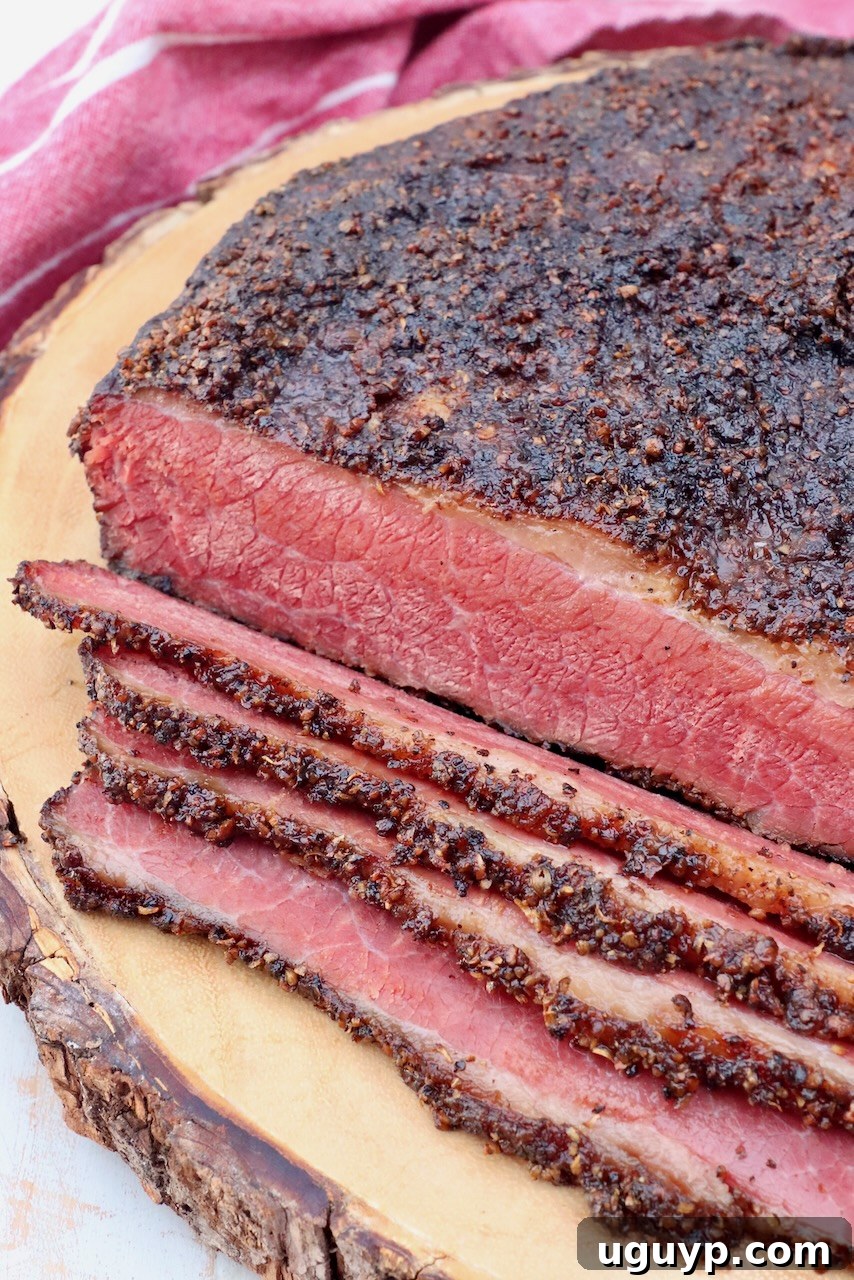 sliced pastrami brisket on wood cutting board, showcasing its beautiful pink color and seasoned bark