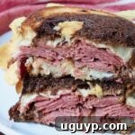 Pastrami reuben sandwich cut in half and stacked on a plate.