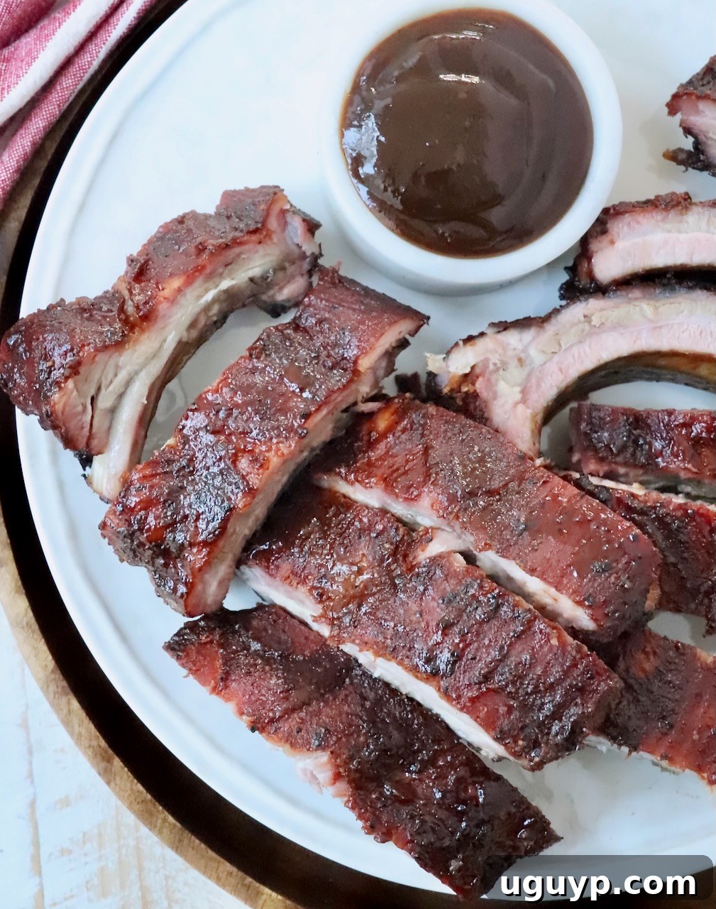 Beautifully sliced, tender smoked baby back ribs, glistening with BBQ sauce, presented on a plate, ready to be enjoyed.