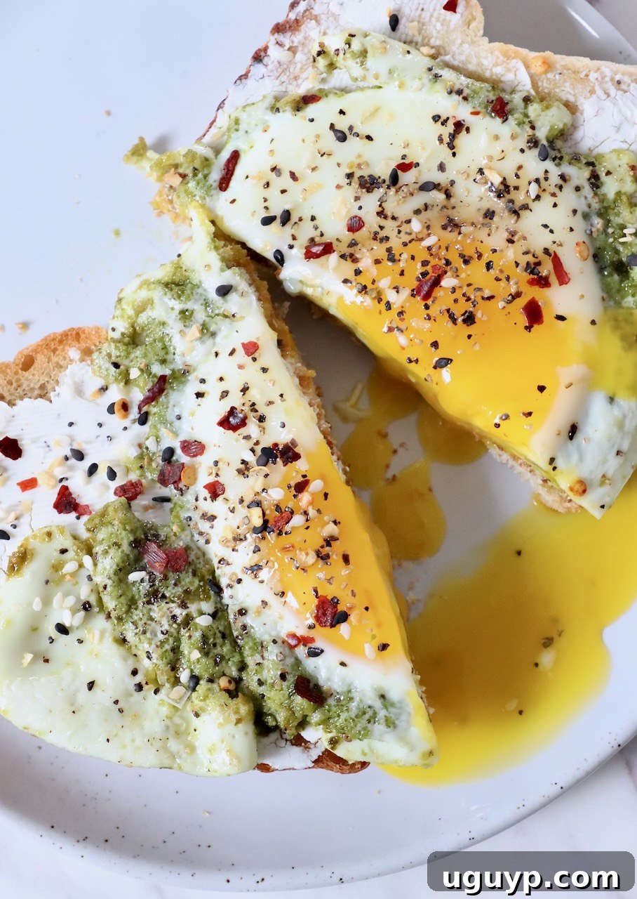 pesto eggs on toast cut in half on plate