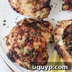 cooked chicken thighs on plate with lemon wedges