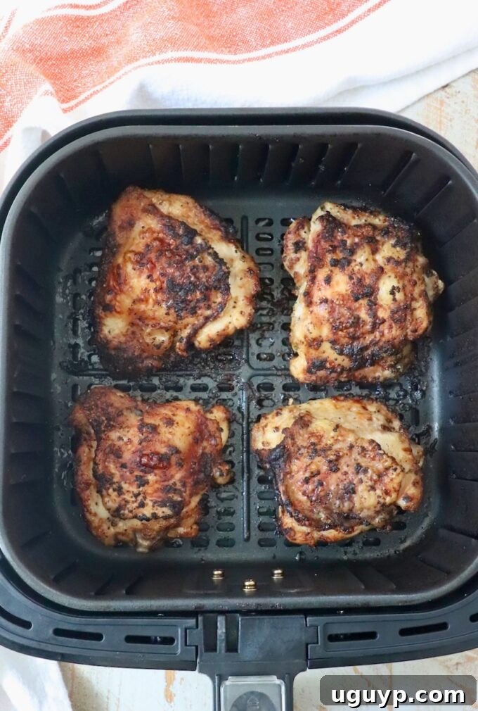 fully cooked, golden-brown bone-in chicken thighs in air fryer basket