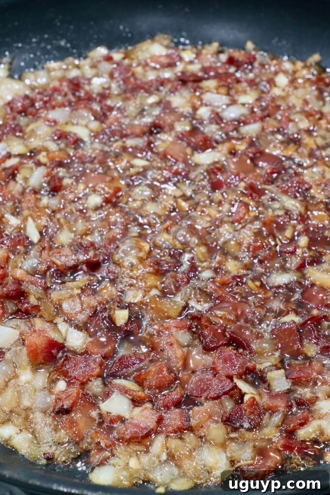 Bacon jam simmering gently in a skillet, thickening and becoming jammy.