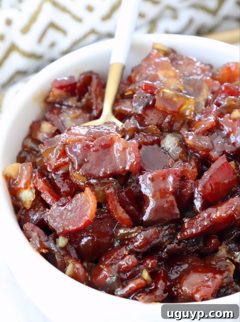 A bowl of rich, thick bacon jam with a spoon, highlighting its inviting texture.