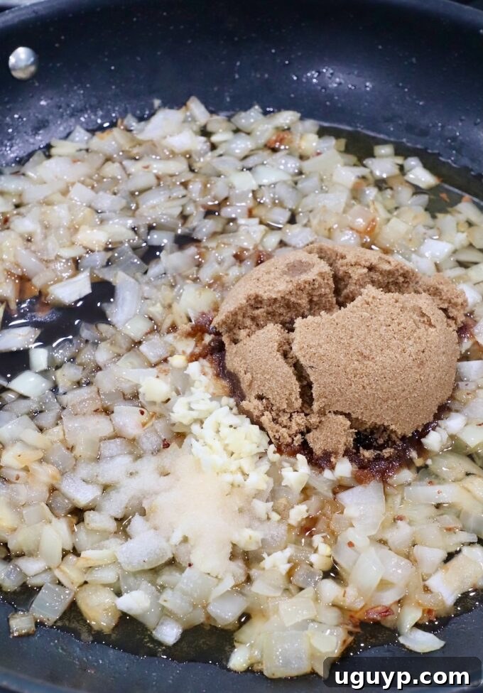 Brown sugar, minced garlic, and salt added to the softened caramelized onions in the skillet.