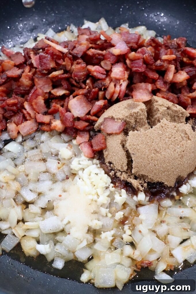 Cooked diced bacon, brown sugar, garlic, and salt mixed with the caramelized onions in the skillet.