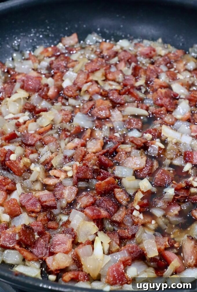 Combined cooked diced bacon and caramelized onions in a skillet, stirring to mix.
