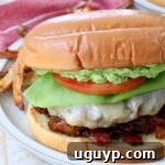 A vibrant California Burger, featuring a juicy patty, melted white cheddar, creamy avocado, and savory bacon jam, ready to be enjoyed.