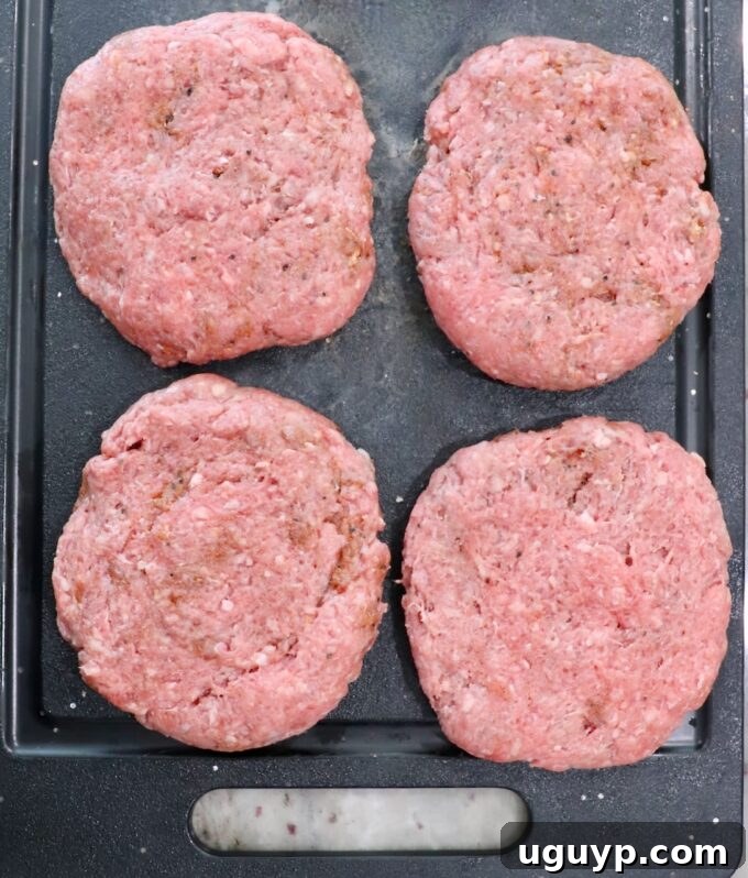 Seasoned burger patties, prepared and ready for grilling, neatly arranged on a cutting board, showcasing their perfect shape and marbling.