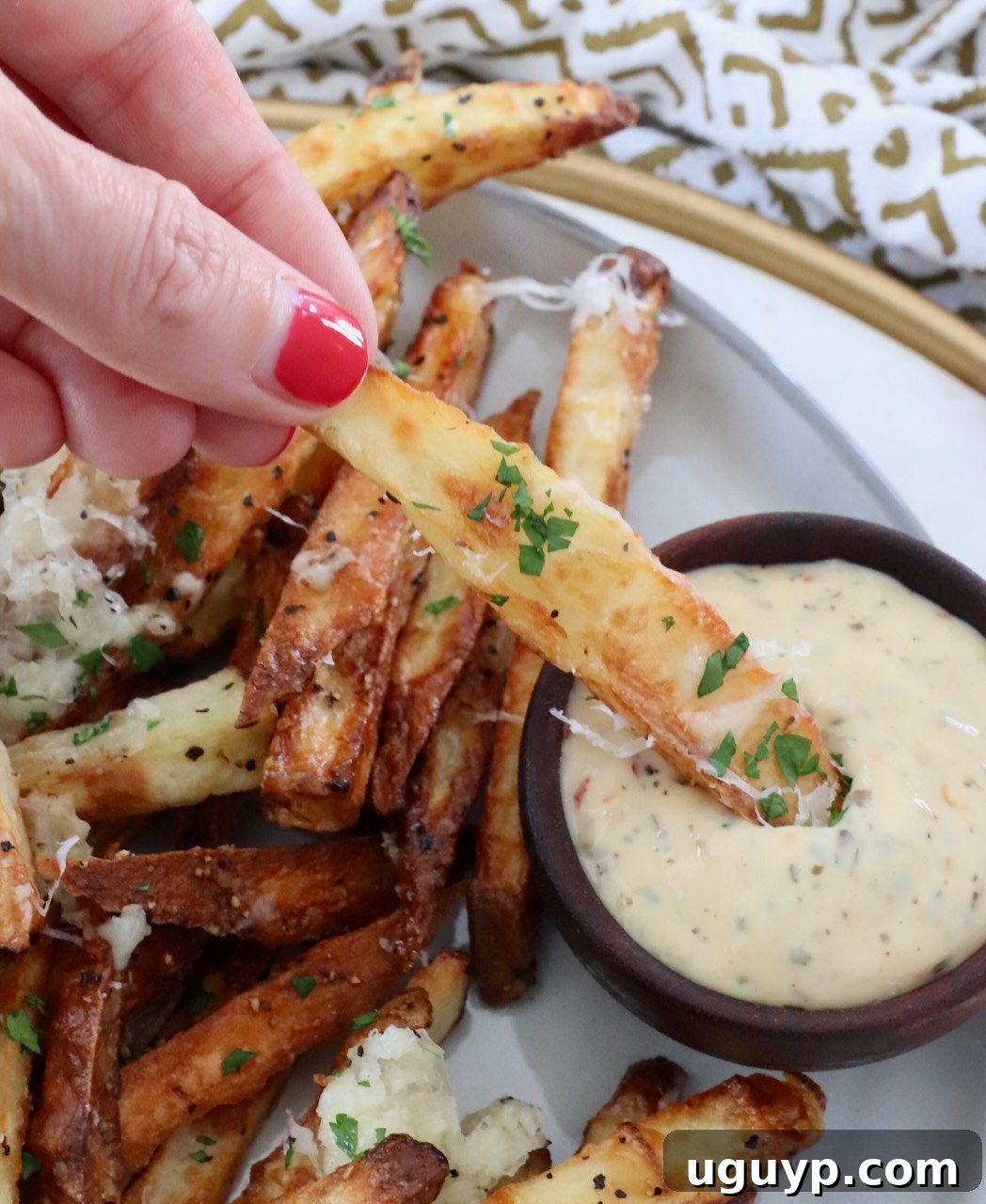 A crispy truffle fry being dipped into a creamy garlic Parmesan sauce, highlighting a perfect pairing.