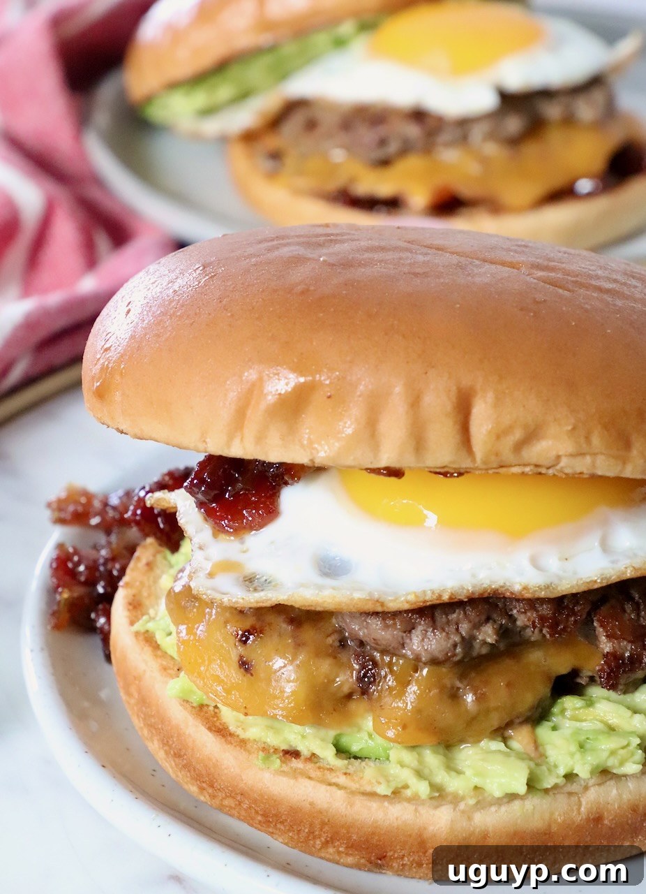 A beautifully plated breakfast burger, adorned with a runny fried egg on top, showcasing its delicious layers.