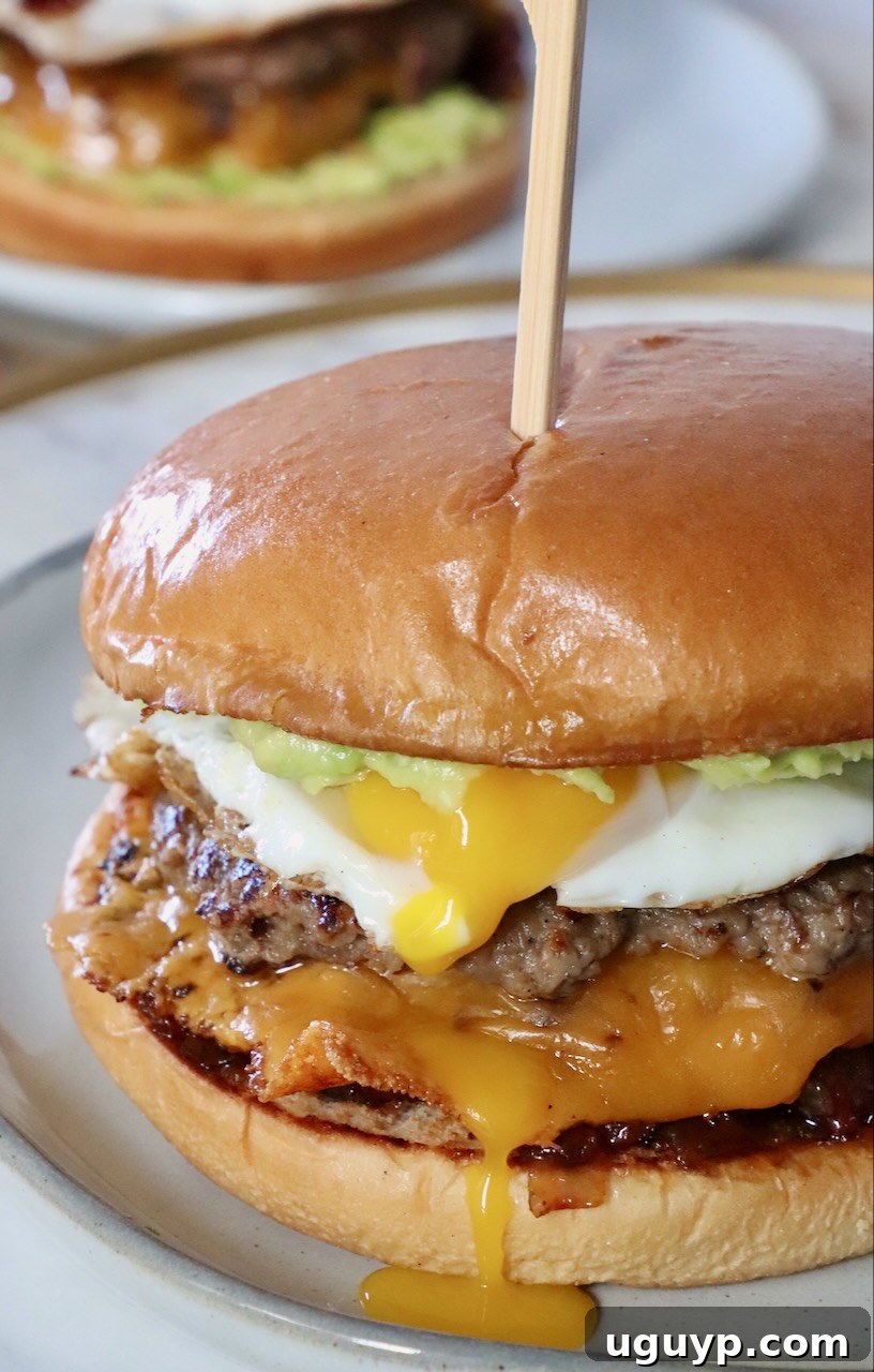 A delectable cheeseburger crowned with a perfectly fried egg, presented on a plate, ready to be enjoyed.
