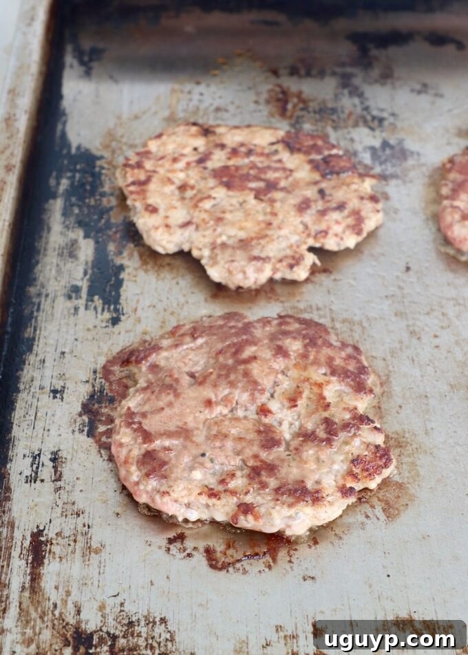Cooked and seared smashed burger patties resting on the flat top, ready for the next step.