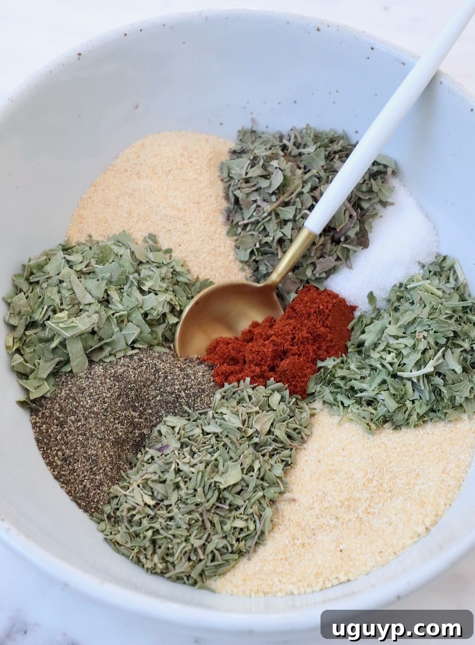 close up of mixed vegetable seasoning in a bowl with a spoon, highlighting the herbs and spices