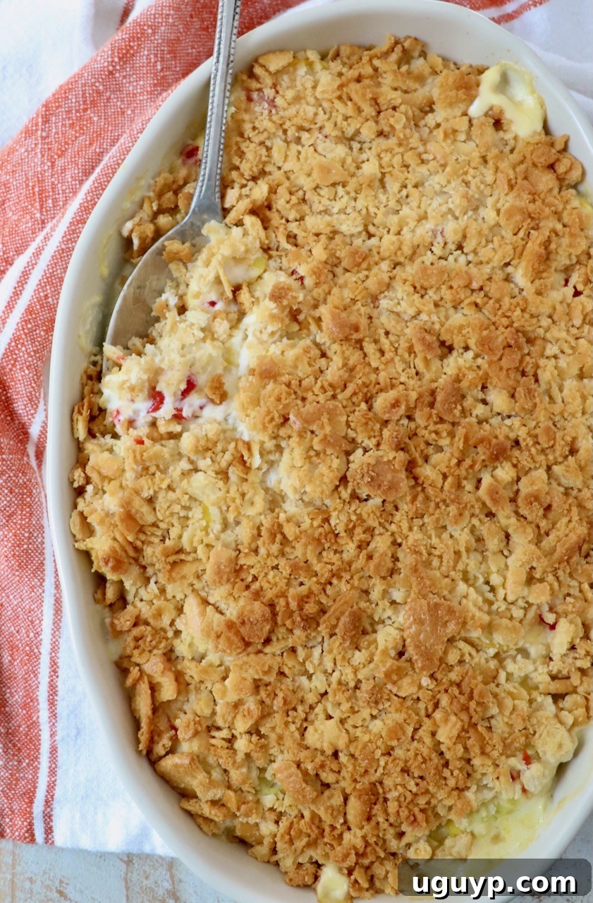 Baked squash casserole in a baking dish, garnished and ready to be served with a serving spoon.