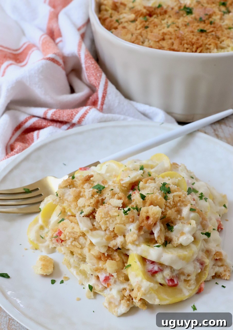 A single serving of squash casserole on a white plate with a fork, showing the creamy texture and crispy topping.
