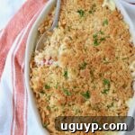 Golden-brown squash casserole with a crunchy Ritz cracker topping, served in a baking dish with a spoon.