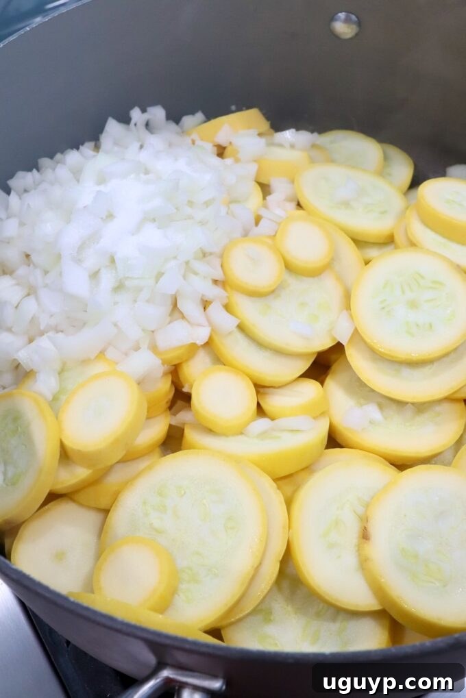 Sliced yellow squash and diced onions ready for cooking in a skillet.