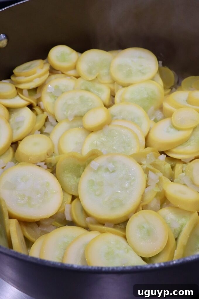 Yellow squash and onions sautéing in a skillet with melted butter.