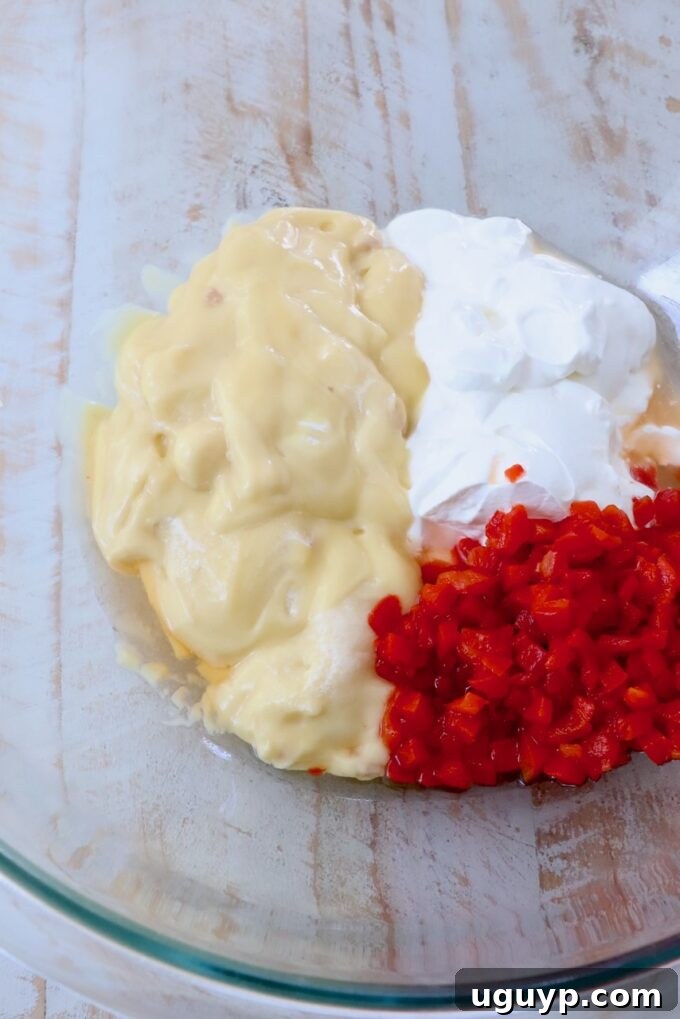 Individual ingredients: cream of chicken soup, sour cream, and chopped pimentos in separate glass bowls.