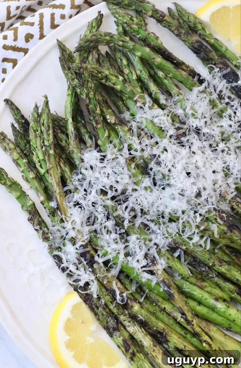 Close-up of perfectly grilled asparagus spears, topped with a generous sprinkle of grated Parmesan cheese.
