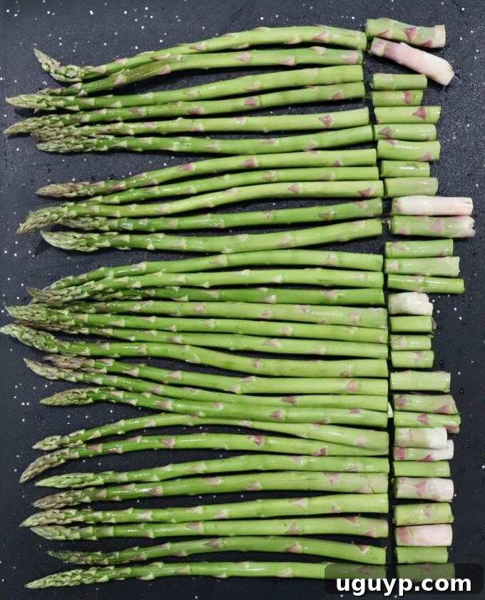 Fresh asparagus on a cutting board, with the woody ends being trimmed off.